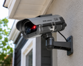 Solar-powered dummy security camera with motion activation and flashing red LED mounted on exterior wall